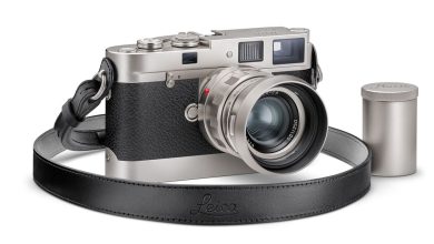 The special edition Leica M Edition 70 camera with a lens and strap attached. Sitting next to it is a metal 35mm film container.