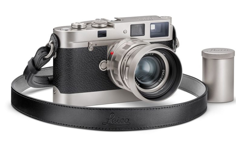 The special edition Leica M Edition 70 camera with a lens and strap attached. Sitting next to it is a metal 35mm film container.