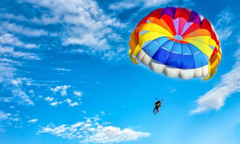 shutterstock 1018105807 rainbow colored parachute against a blue sky and cirrus clouds