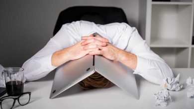 Man hiding under laptop in frustration because of mistakes, failure