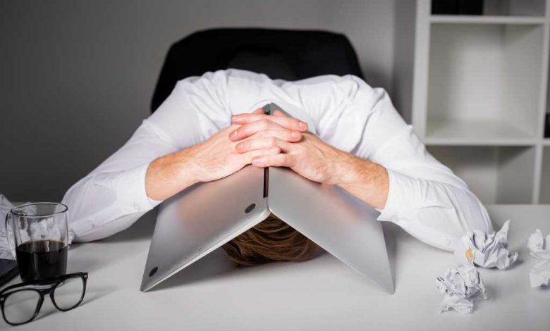 Man hiding under laptop in frustration because of mistakes, failure