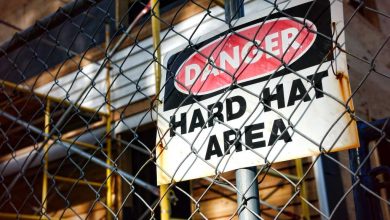 shutterstock 77002051 Danger hard hat area safety warning sign chain link fence construction site