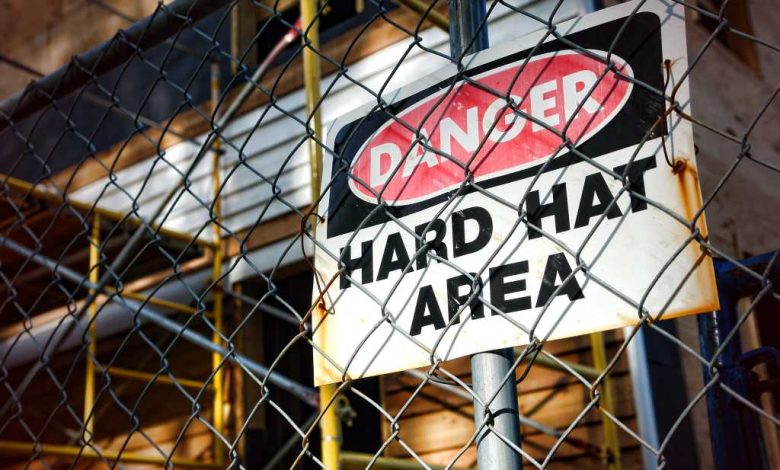 shutterstock 77002051 Danger hard hat area safety warning sign chain link fence construction site