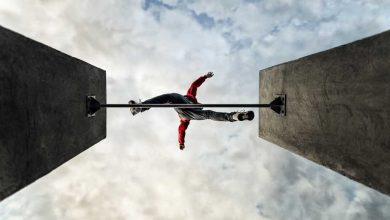 man jumps over obstacle, parkour leaps across gap, view from below looking up at cloud filled sky