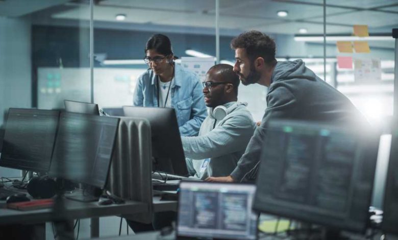 Diverse Group of Professionals Meeting in Modern Office: Brainstorming IT Programmers Use Computer Together, Talk Strategy, Discuss Planning. Software Engineers Develop Inspirational App Program