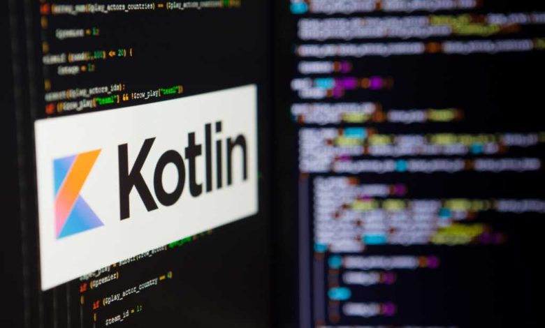 A computer screen shows the Kotlin logo against a backdrop of code.