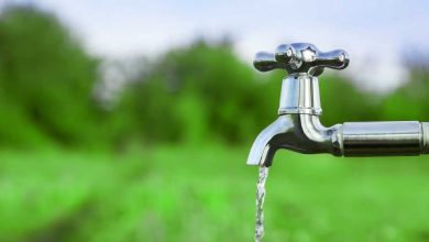 shutterstock 434035804 water flowing from a silver outdoor tap amid green fields and green trees