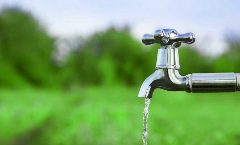 shutterstock 434035804 water flowing from a silver outdoor tap amid green fields and green trees