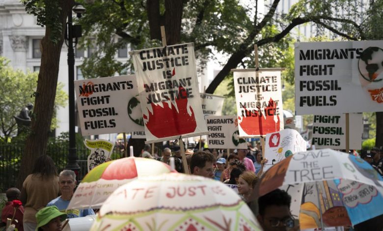 A crowd gathers with people carrying signs that say “climate justice is migrant justice” and “migrants fight fossil fuels.”