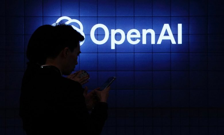 Visitor look at their phone next to an Open AI's logo during the Mobile World Congress (MWC), the telecom industry's biggest annual gathering, in Barcelona on February 26, 2024. The world's biggest mobile phone fair throws open its doors in Barcelona with the sector looking to artificial intelligence to try and reverse declining sales. (Photo by PAU BARRENA/AFP via Getty Images)