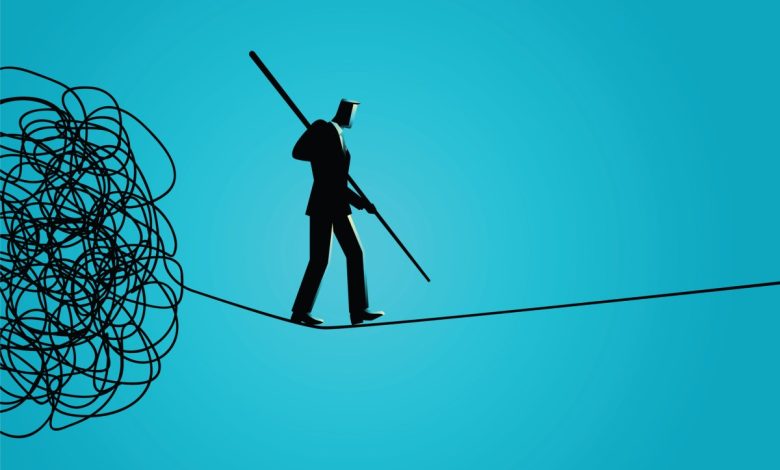 Businessman walking away carefully from tangled rope