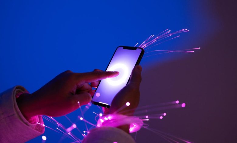 Person holding a smartphone with futuristic neon background