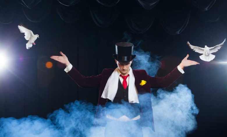 Magician with two flying white Doves on a black background shrouded in mysterious blue smoke