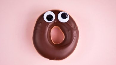 Close-up of a surprised doughnut with chocolate icing and googly eyes.