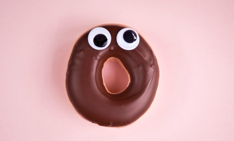 Close-up of a surprised doughnut with chocolate icing and googly eyes.