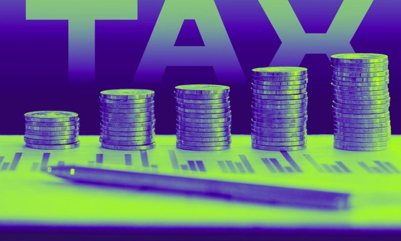 Coins piled up like a bar chart on top of tax documents with the word TAX in background.